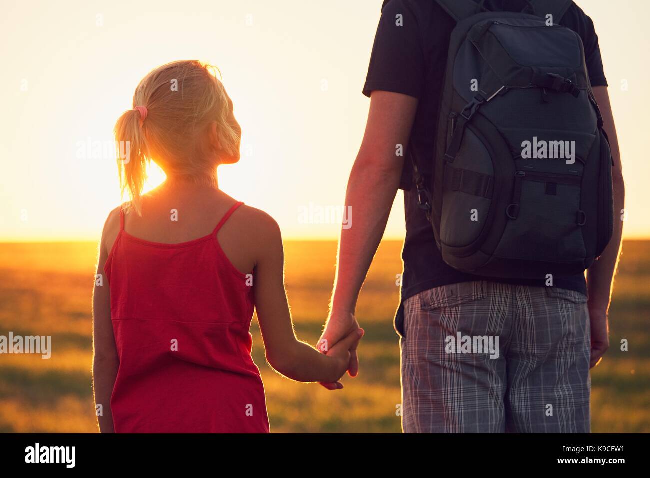 Viaggio estivo in campagna. ragazza con mano il suo padre al tramonto. - Back lit Foto Stock