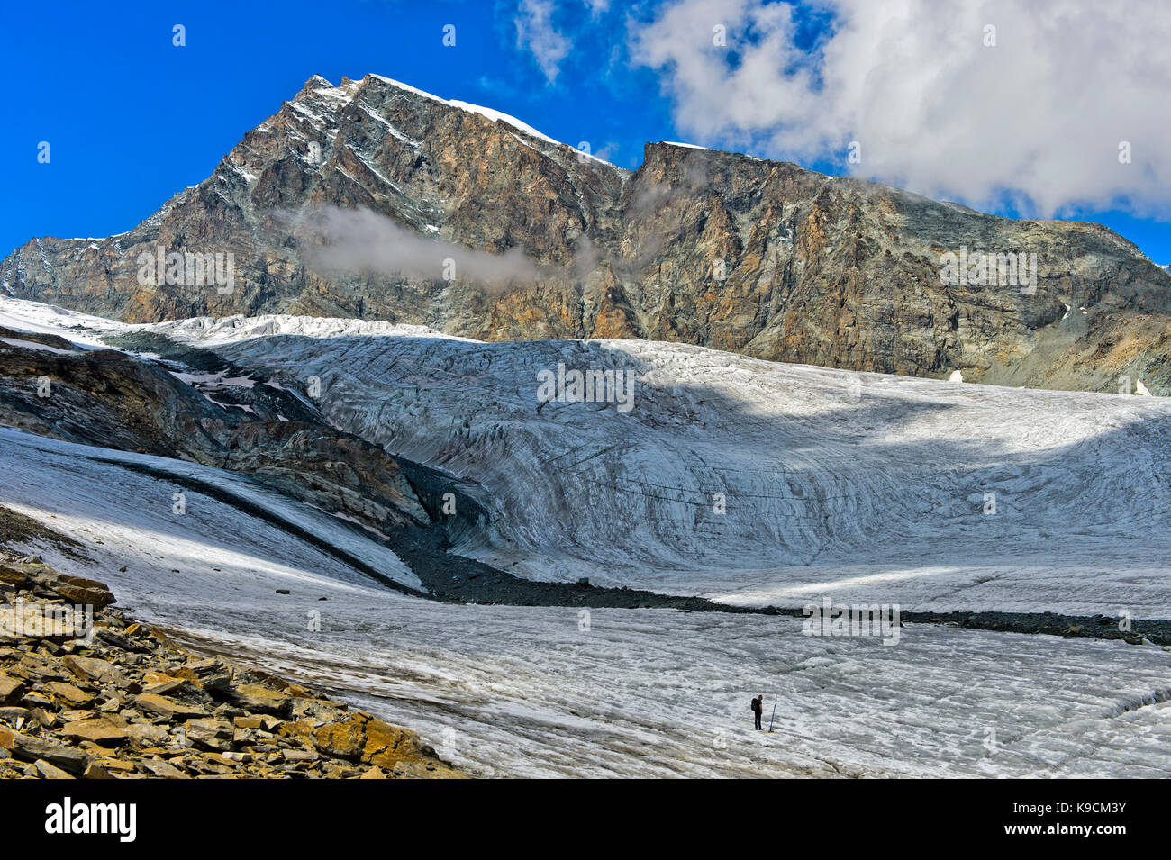 Escursionista attraversando il ghiacciaio allalingletscher lungo il sentiero del ghiacciaio felskinn-mattmark, picco allalinhorn dietro, Saas fee, Vallese, Svizzera Foto Stock