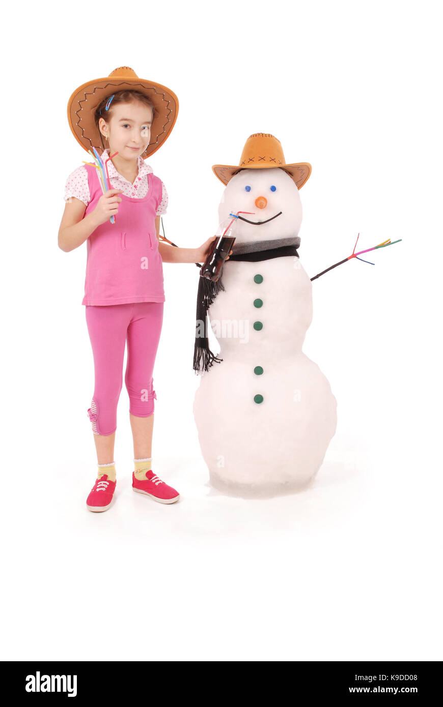 Carina ragazza con una bottiglia di cola nei pressi di un pupazzo di neve con sciarpa e cappello su sfondo bianco Foto Stock
