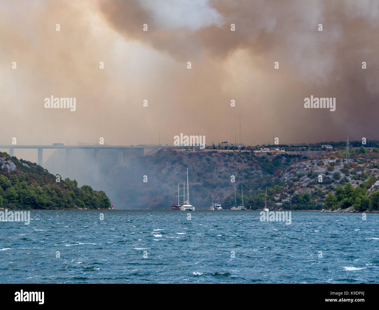 Incendio di foresta in Croazia, estate disastro naturale vicino al parco nazionale di Krka, Regione di Sebenico, Barche e yachts fuoriuscite di Città di Skradin dal fumo Foto Stock