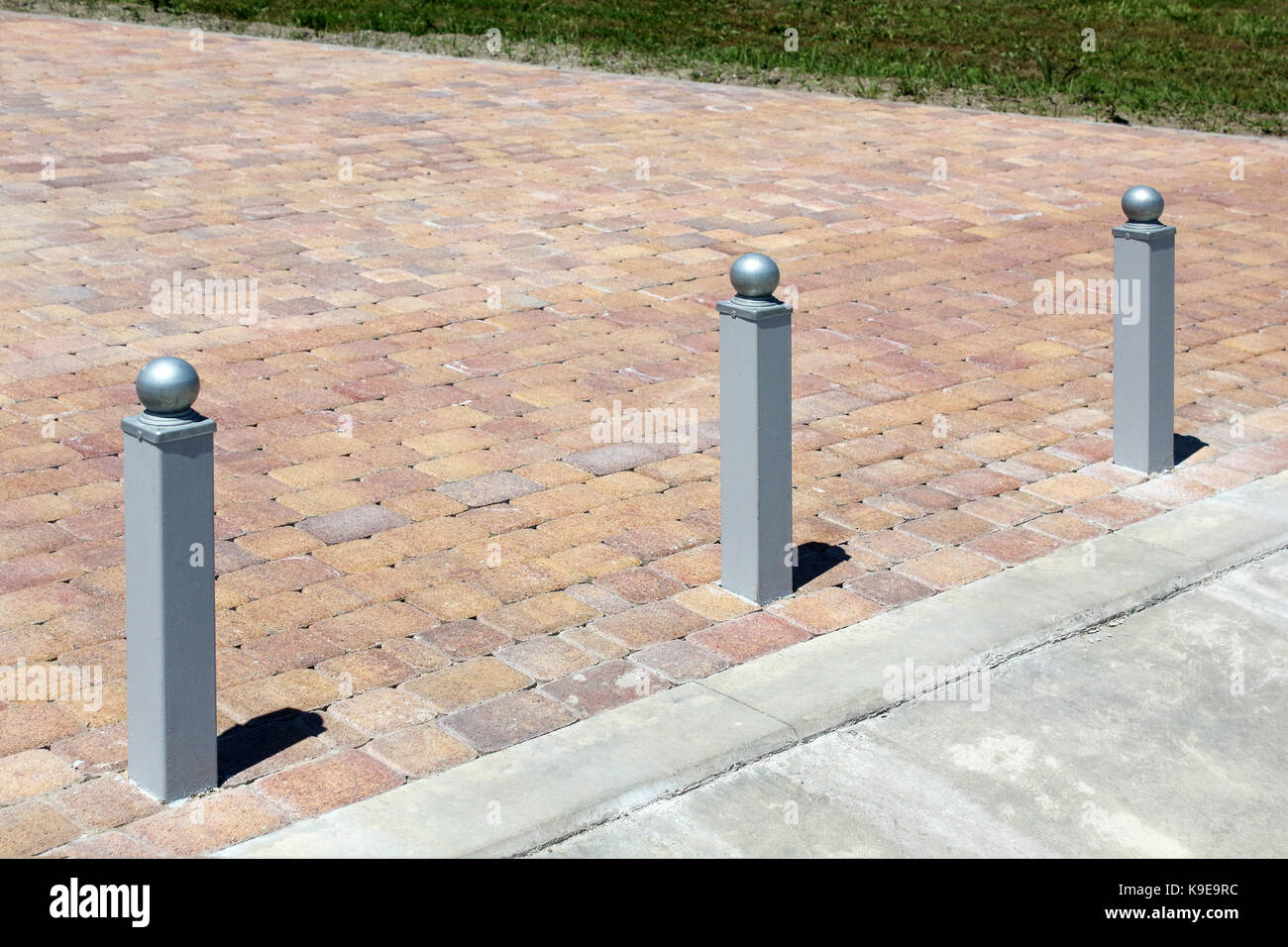 Tre colonnine di metallo attraverso il pavimento di piastrelle foto Foto Stock