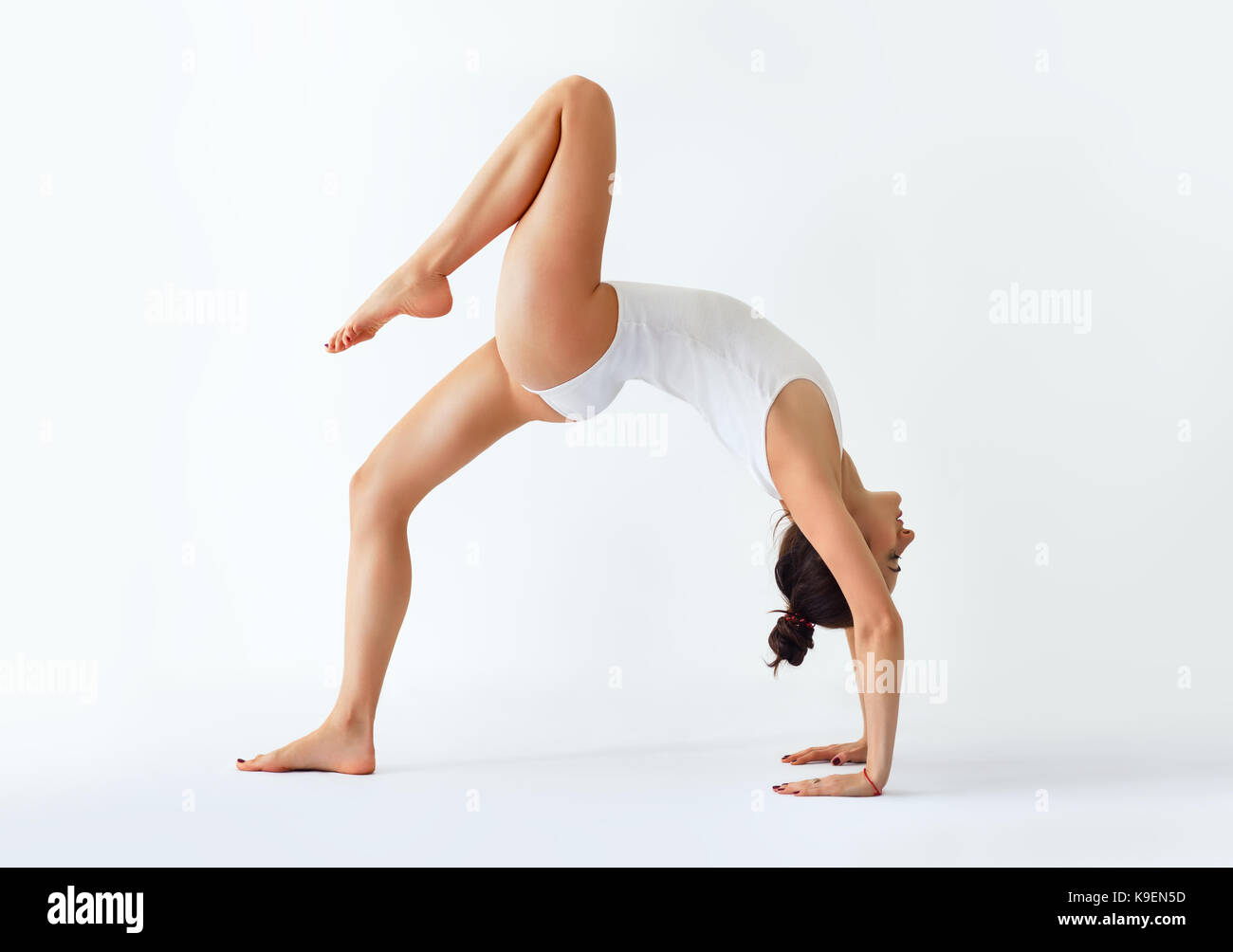 Giovane donna fare yoga asana pongono a ponte con la gamba destra verso l'alto. ekopada dhanurasana più a destra Foto Stock