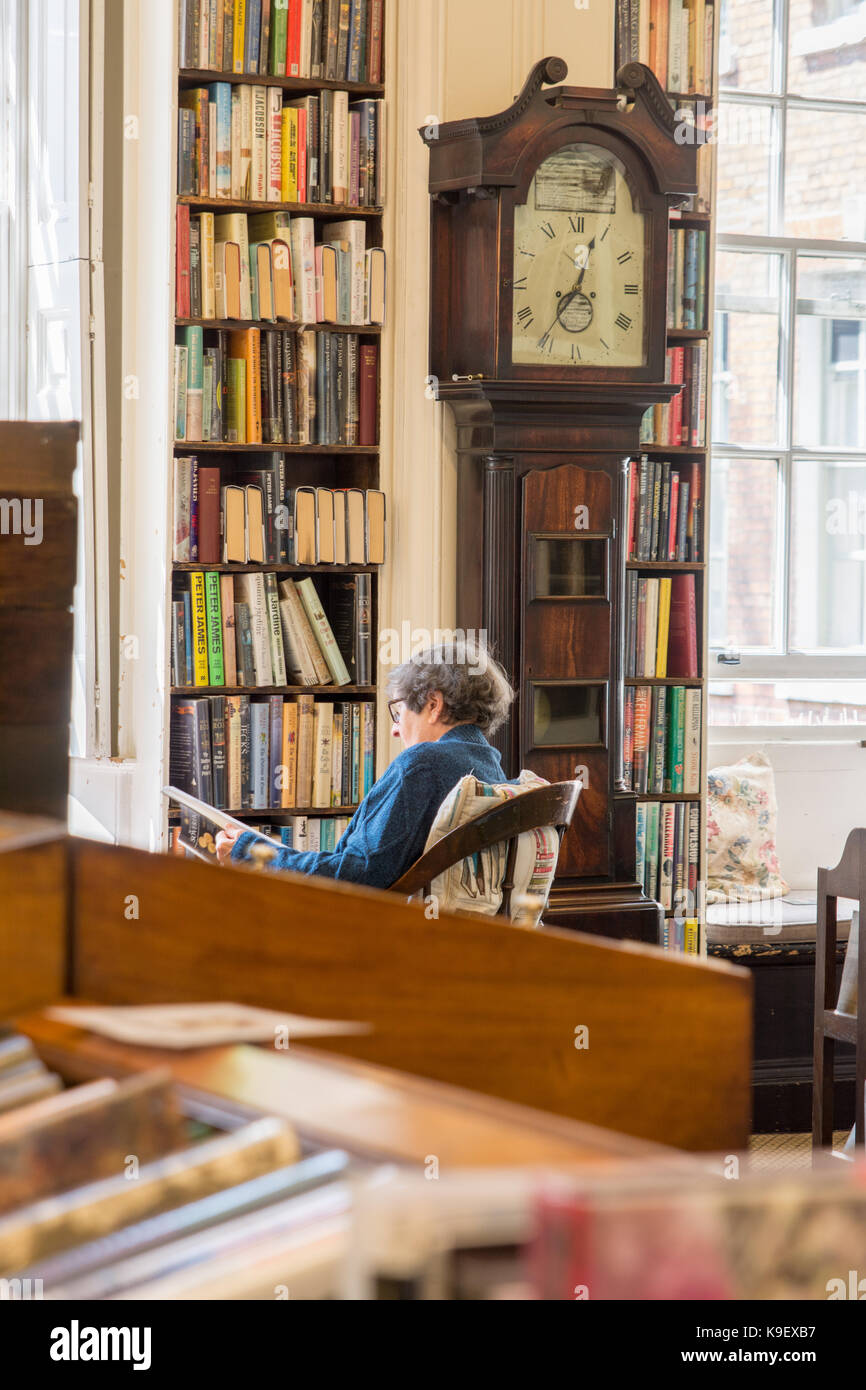 Signora lettura nella storica bromley house library nottingham davanti di orologio del nonno Foto Stock