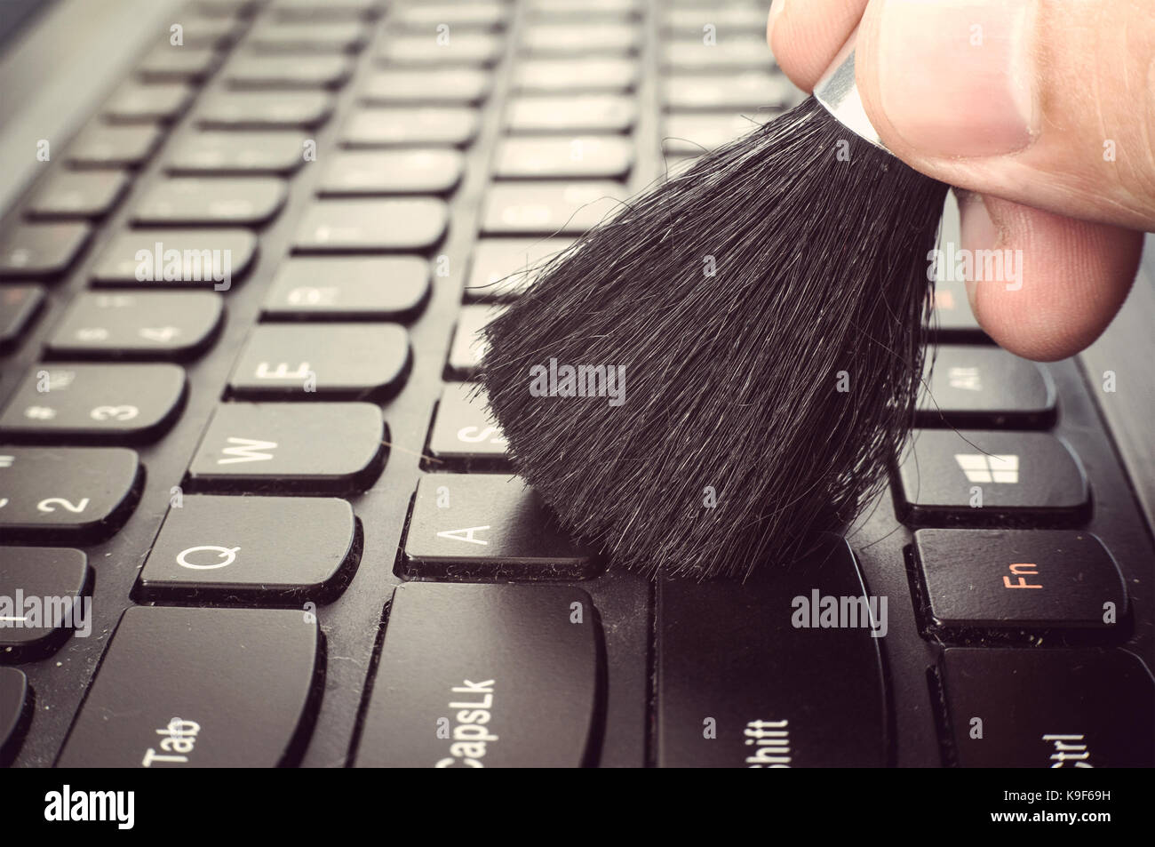 Sporca la pulizia della tastiera del computer. mano maschio con una  spazzola per rimuovere la polvere dalla tastiera close-up Foto stock - Alamy