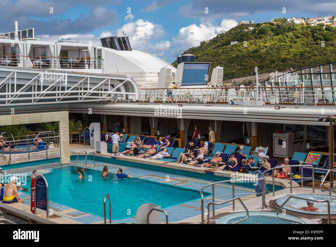 I passeggeri a prendere il sole e nuotare in a bordo piscina su una crociera nei Caraibi Liner ancorato in Philipsburg, Sint Maarten. Foto Stock