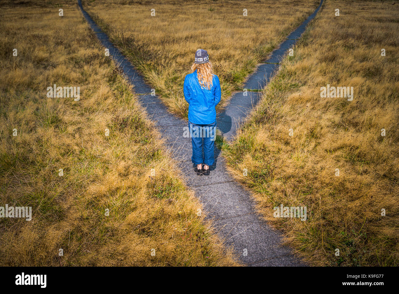 Una donna in piedi di fronte a un bivio pronto a prendere una decisione. Foto Stock
