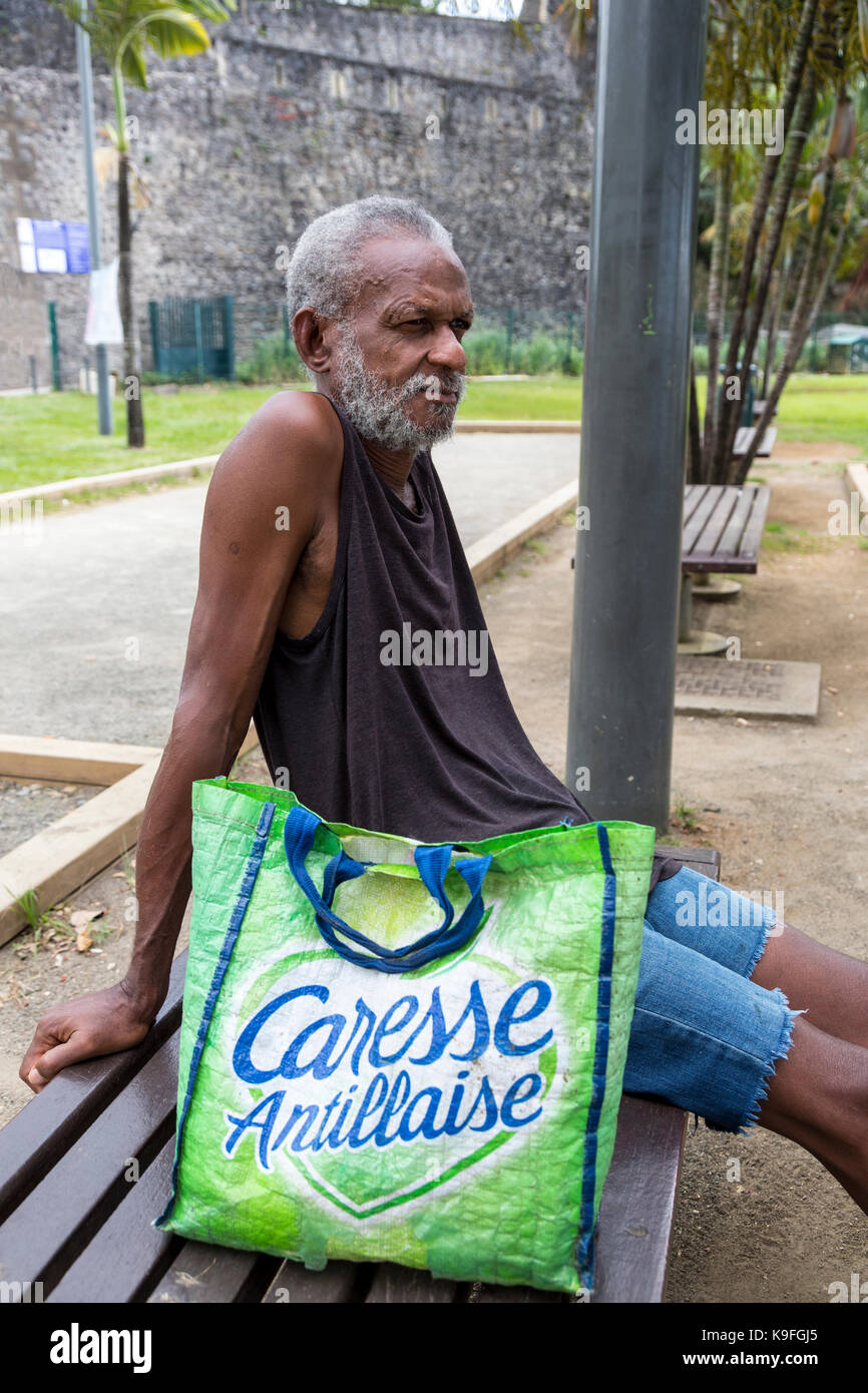 Fort-de-France, Martinica. Uomo anziano in appoggio su una panchina nel parco. Foto Stock