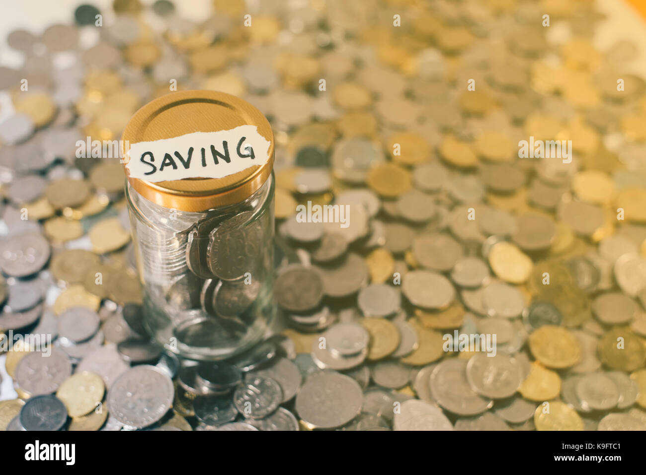 Monete in un vasetto di vetro con nota scritta ' risparmio '. tono dorato. concetto di risparmio. malaysia valuta Foto Stock