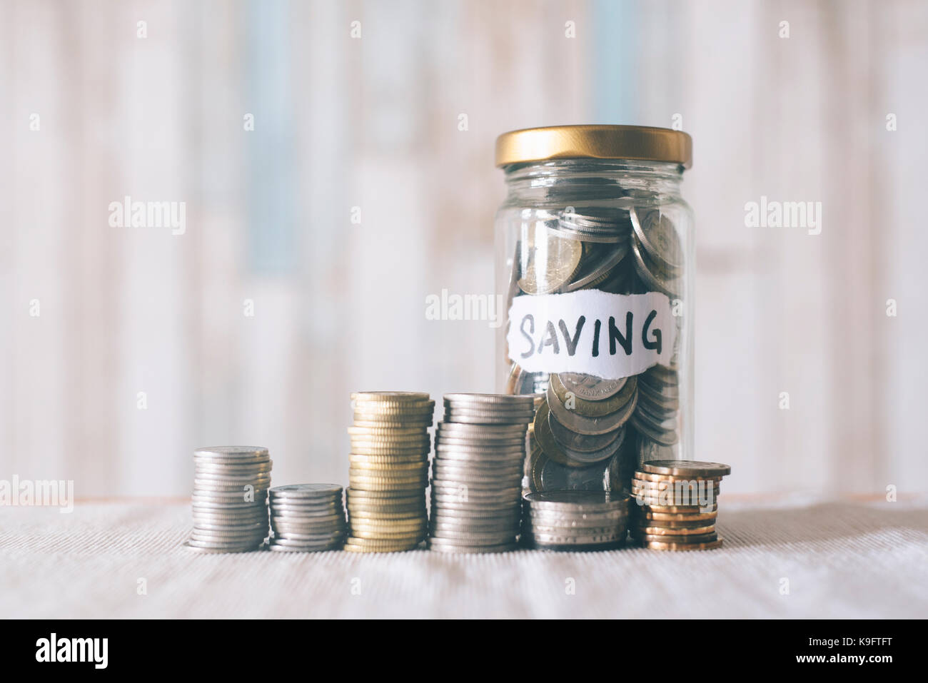 Monete e il vasetto di vetro marcato risparmio ' ' mettere in tavola. Il risparmio di denaro per il futuro. concetto di risparmio Foto Stock