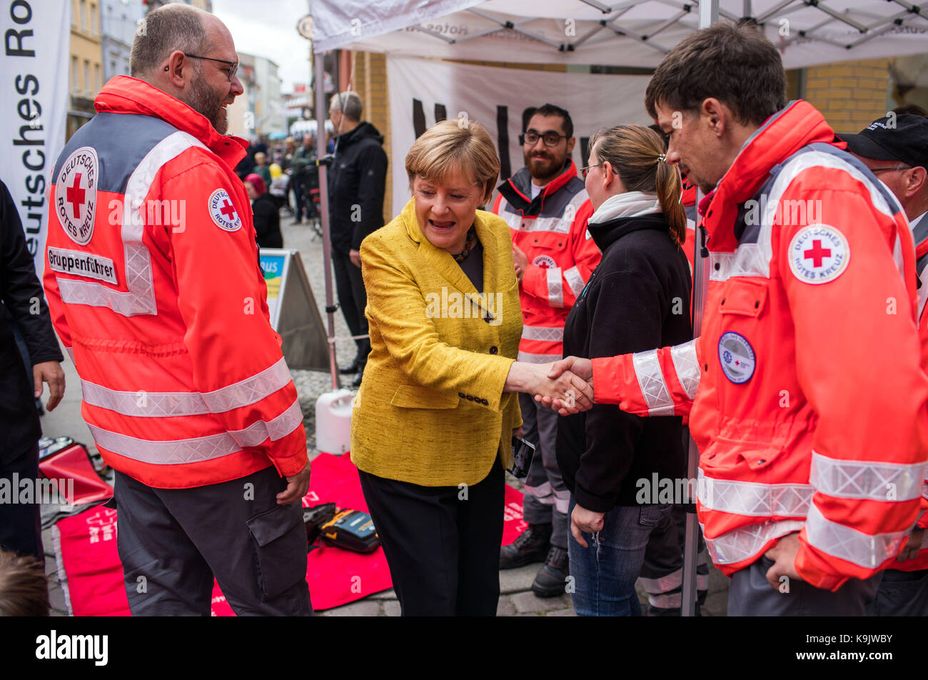 Stralsund, Germania. 23 Sep, 2017. Il cancelliere tedesco Angela Merkel (m) riceve informazioni ad uno stand della Croce Rossa tedesca per il progetto settimana 'resuscitation' mentre passeggiando per il centro storico di Stralsund, Germania, 23 settembre 2017. Il progetto settimana dell'università di medicina di greifswald persone vengono insegnate resuscitarlo. Dopo la visita di Stralsund Merkel parteciperà anche raccolto una celebrazione in lauterbauch sull isola di ruegen, così come la città di Greifswald. Credito: Jens büttner/dpa-zentralbild/dpa/alamy live news Foto Stock