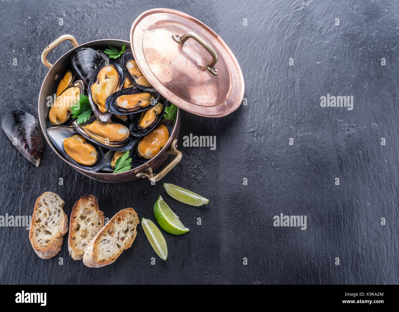 Bollito di cozze in padella di rame su sfondo di grafite. Foto Stock