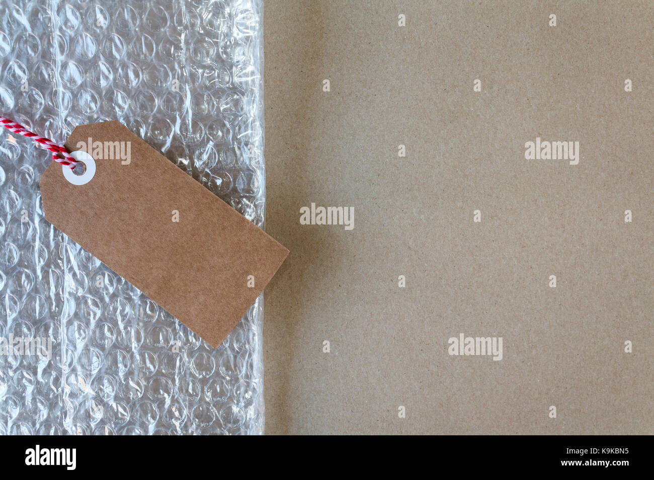 Spese postali e di materiali di imballaggio con bolle e un dono tag su carta da imballaggio marrone con spazio di copia Foto Stock