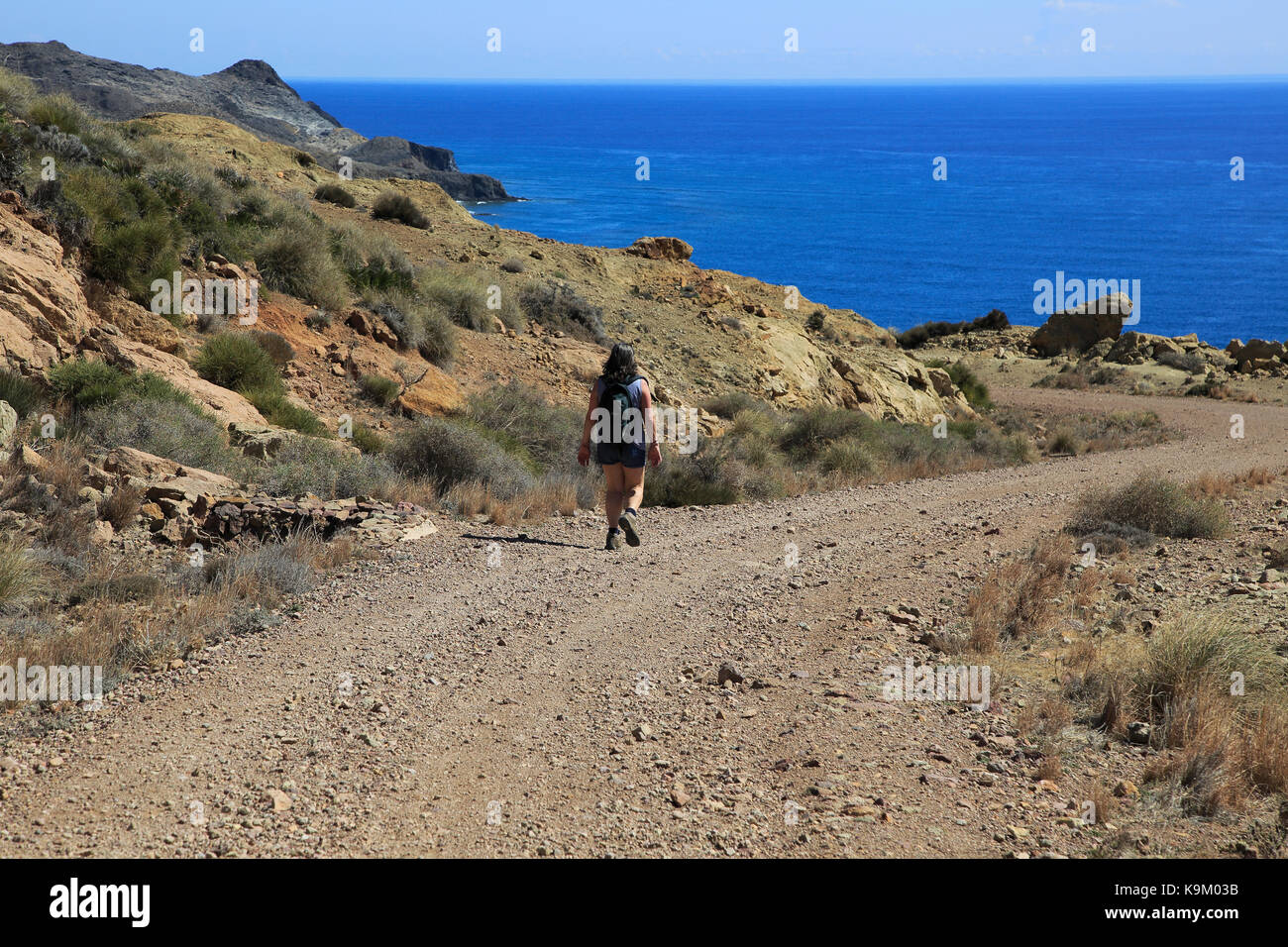 Donna camminando lungo il sentiero costiero nel Parco Nazionale Cabo de Gata, nei pressi di San José, Almeria, Spagna Foto Stock
