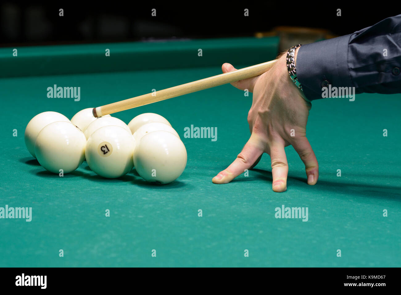 Un giocatore di braccio con la cue su un tavolo da pool pronto per la corsa a sfera Foto Stock