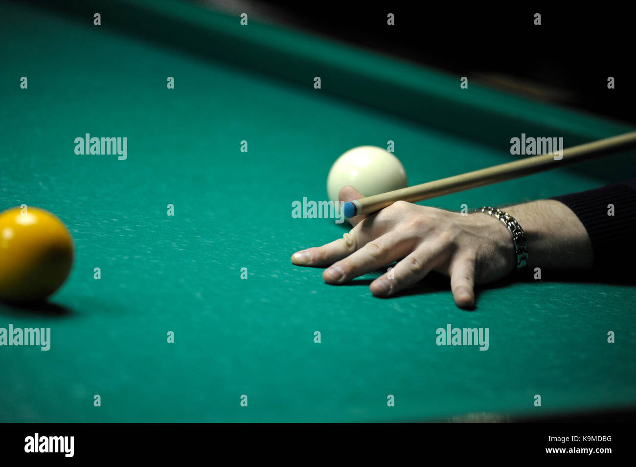 Un giocatore di braccio con la cue su un tavolo da pool pronto per la corsa a sfera Foto Stock