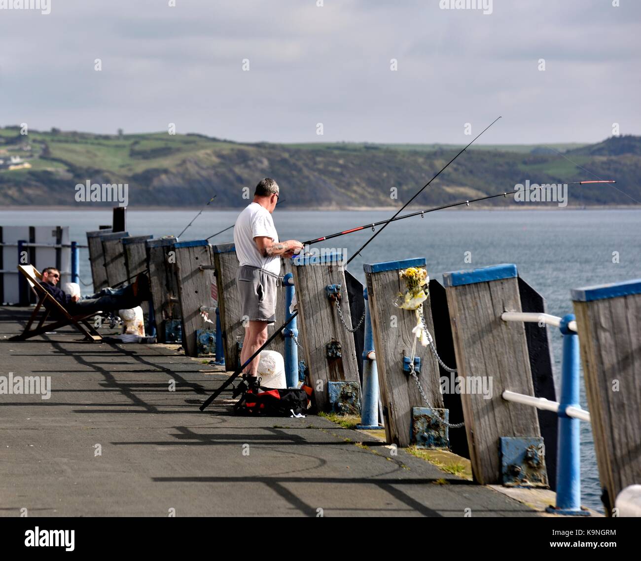 Due uomini di pesca sul molo di Weymouth Dorset England Regno Unito Foto Stock