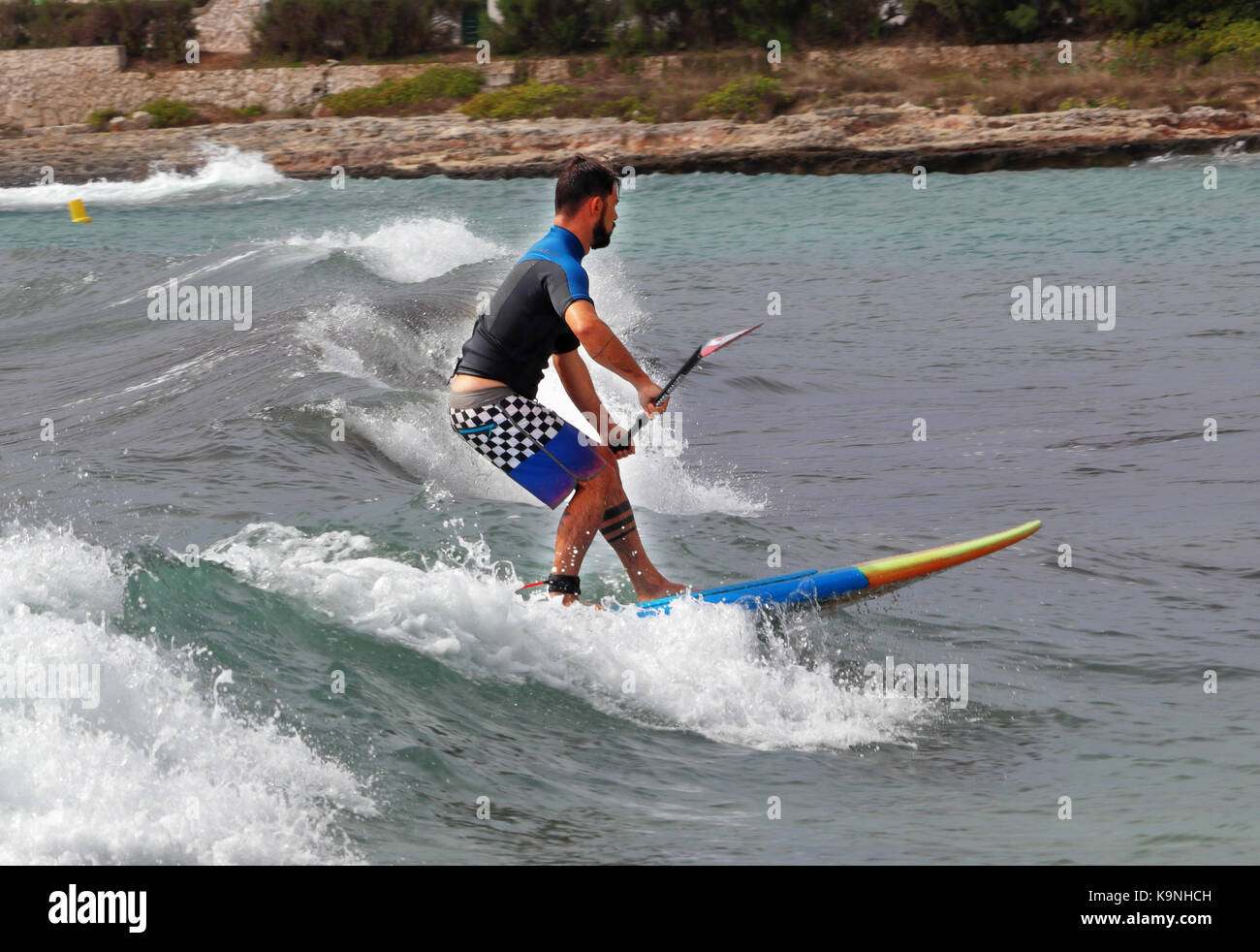 I minorchini resort di punta prima nel mar mediterraneo con maschio scheda paddle surf Foto Stock