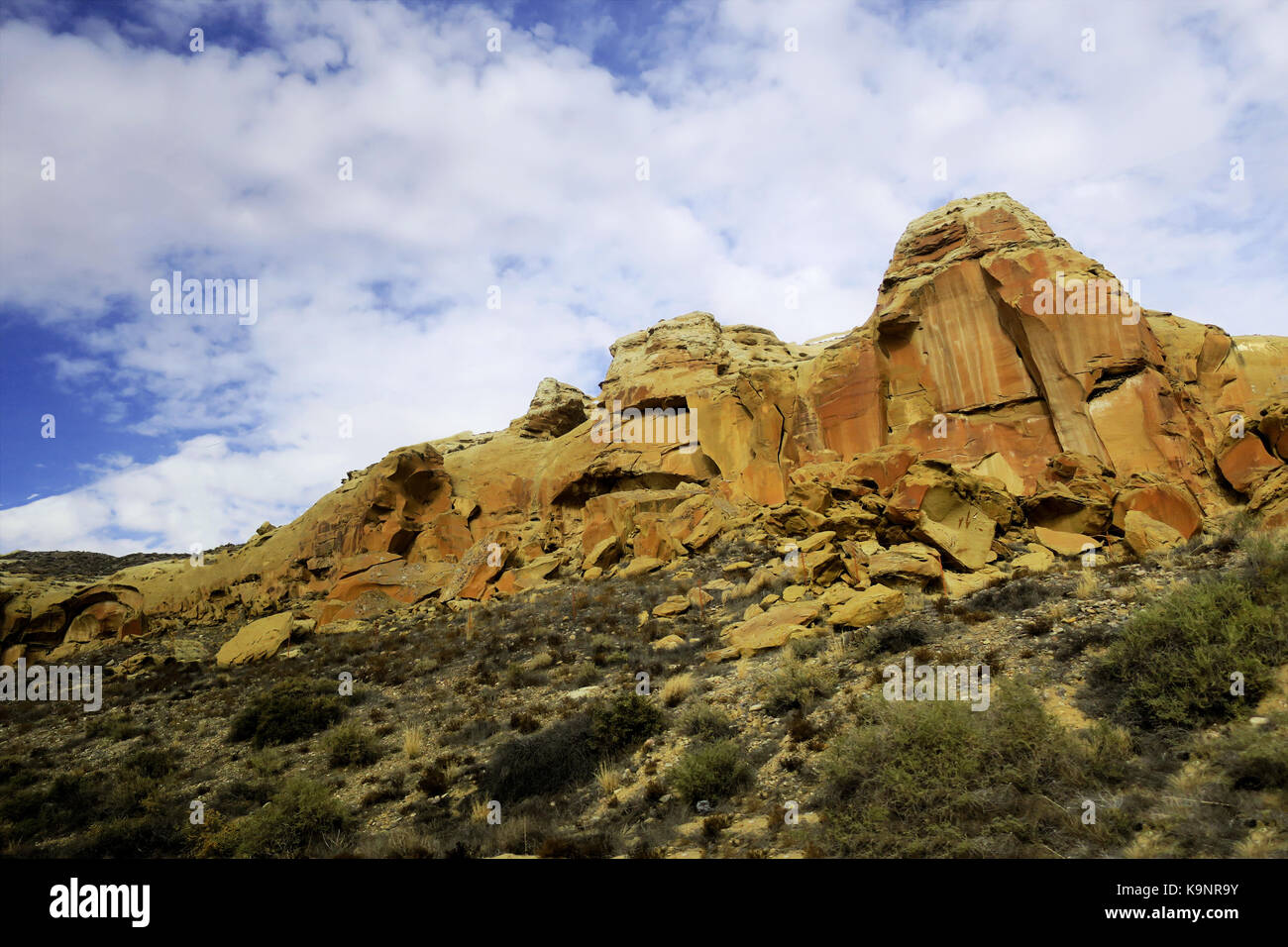 Una bella abbronzatura naturale parete di roccia su un cielo blu con galleggianti, puffy nuvole bianche. Foto Stock