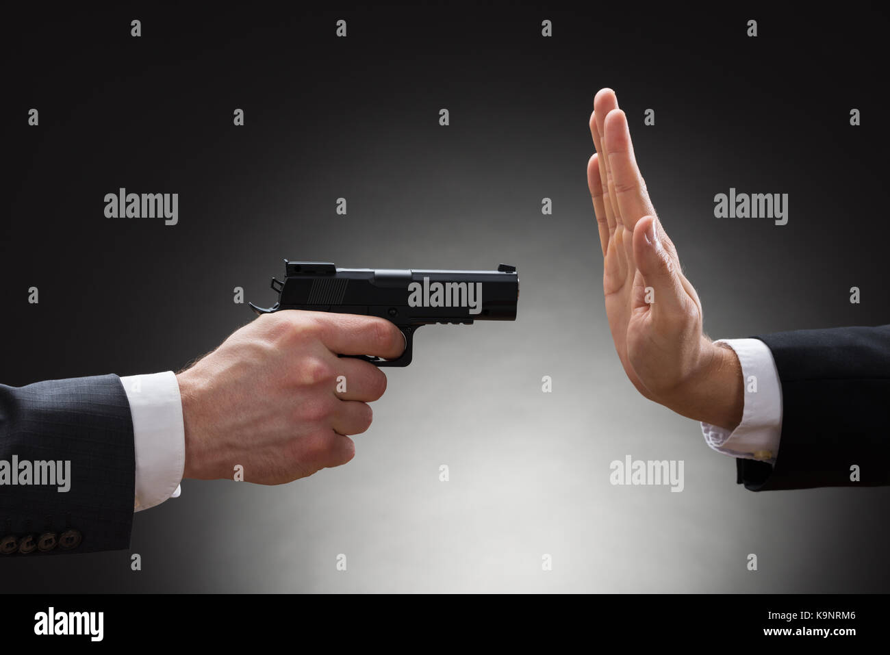 Close-up di imprenditore mano con la pistola rivolta verso i mediatori gesticolando stop Foto Stock