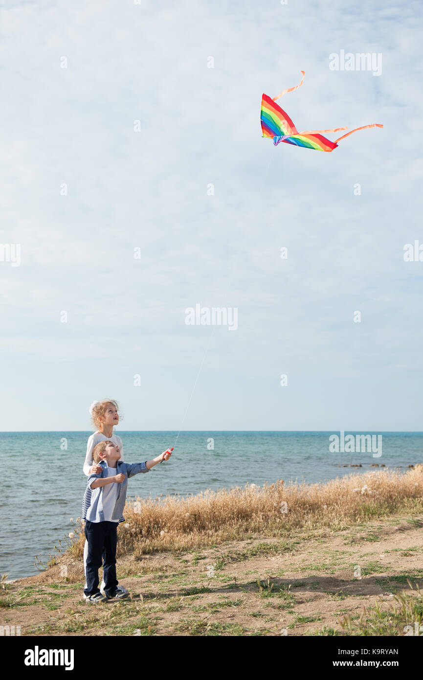 Piccolo Ragazzo e ragazza con un aquilone vola nel cielo sullo sfondo del  mare Foto stock - Alamy