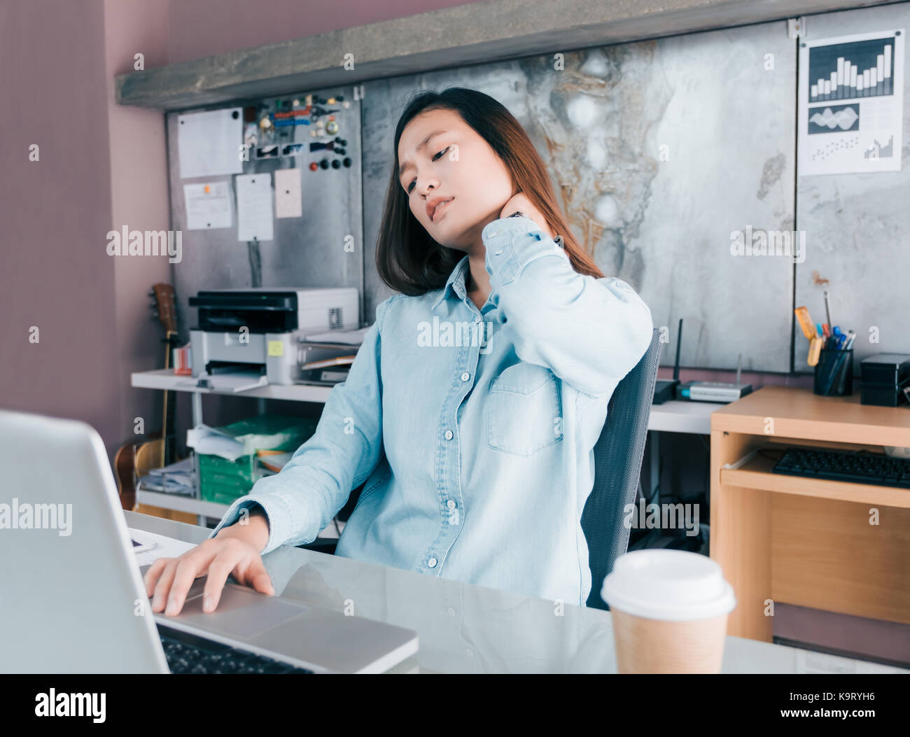 Asian creative designer donna la sua cattura dolore al collo dal lavoro duro per lungo tempo alla parte anteriore del computer portatile sulla scrivania in ufficio,Ufficio concetto di sindrome. Foto Stock