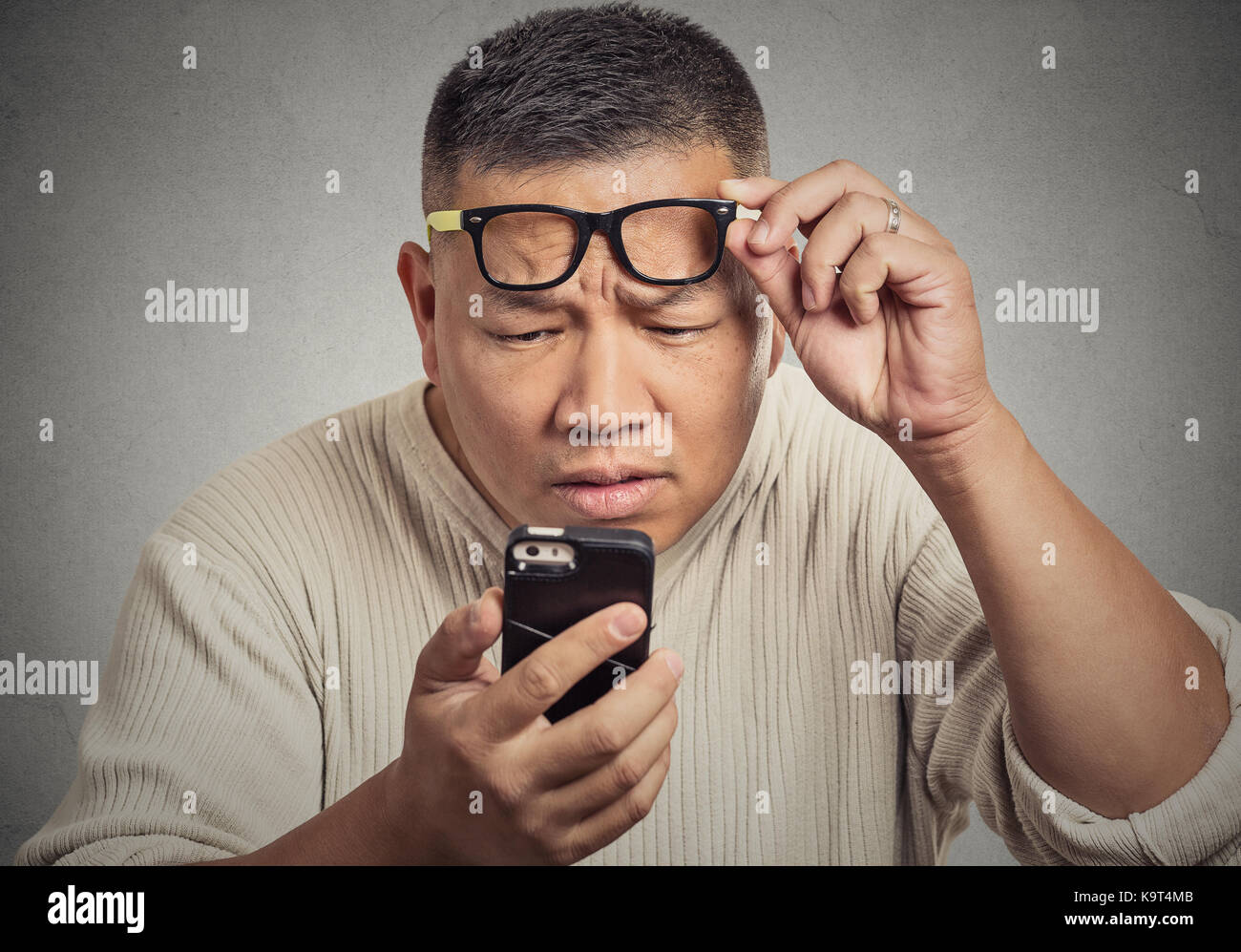 Closeup ritratto headshot uomo di mezza età con gli occhiali problemi nella visualizzazione di telefono cellulare schermo a causa di problemi di visione. cattivo testo messaggio negativo. Foto Stock