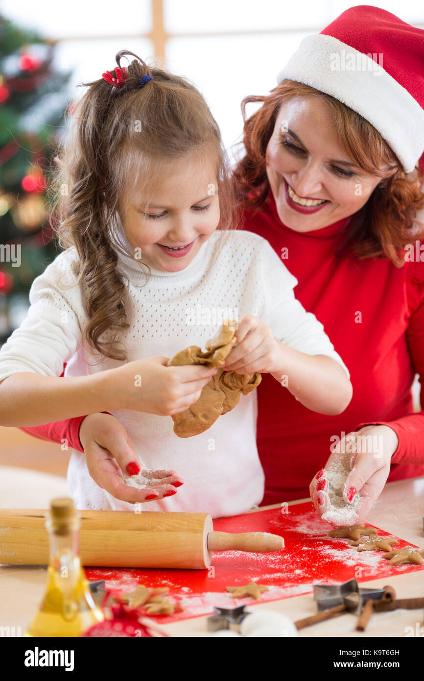 La ragazza del bambino con sua madre la cottura biscotti di Natale in cucina Foto Stock