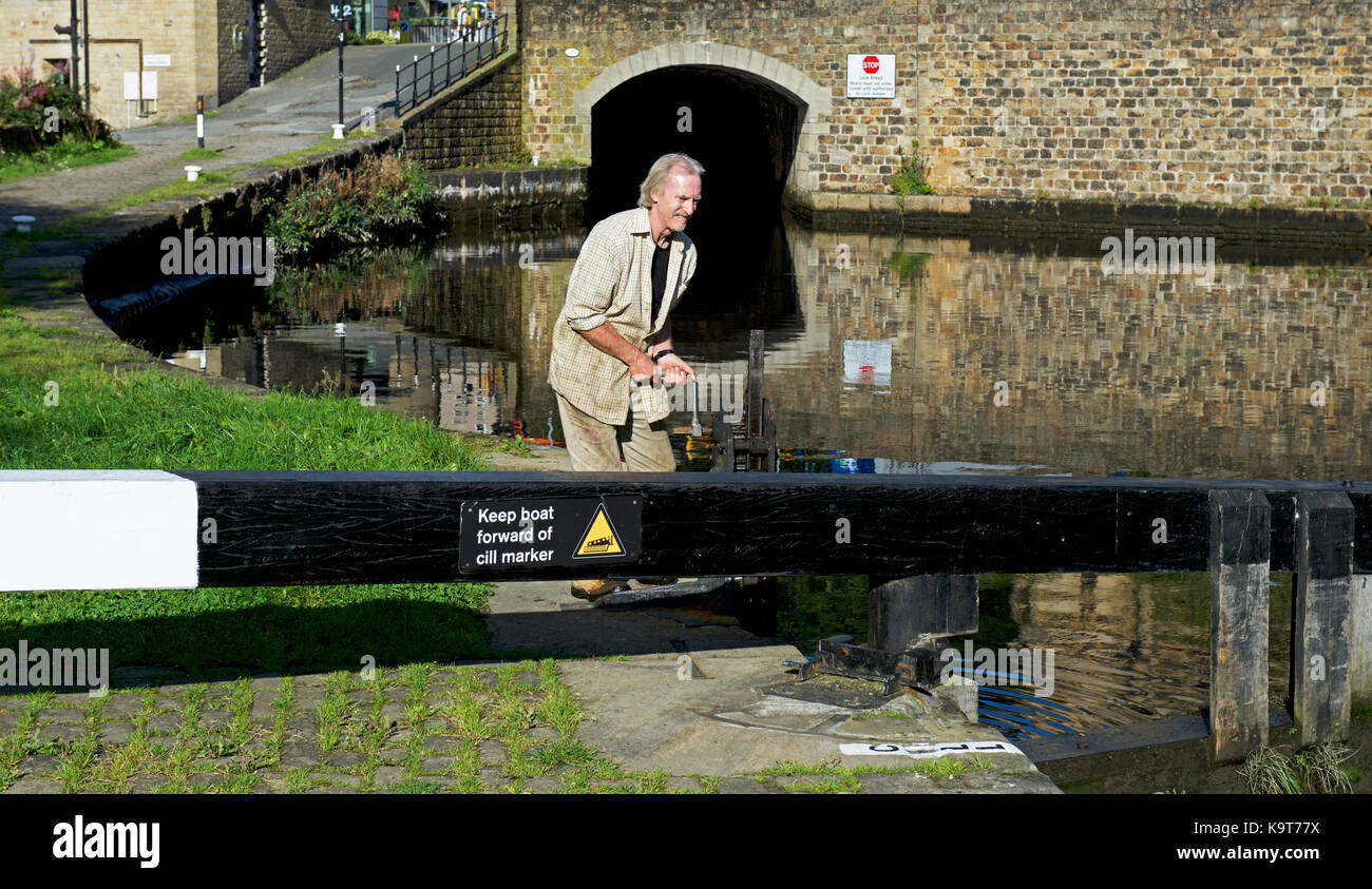 Uomo di blocco apertura cancello a Rochdale Canal a Sowerby Bridge, Calderdale, West Yorkshire, Inghilterra, Regno Unito Foto Stock