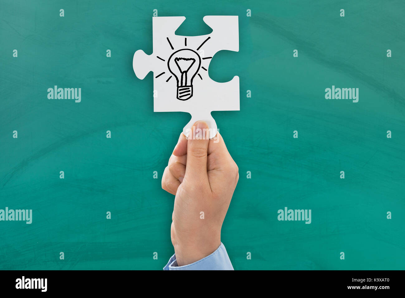 Close-up di persona a mano che mostra il simbolo della lampadina sul puzzle Foto Stock