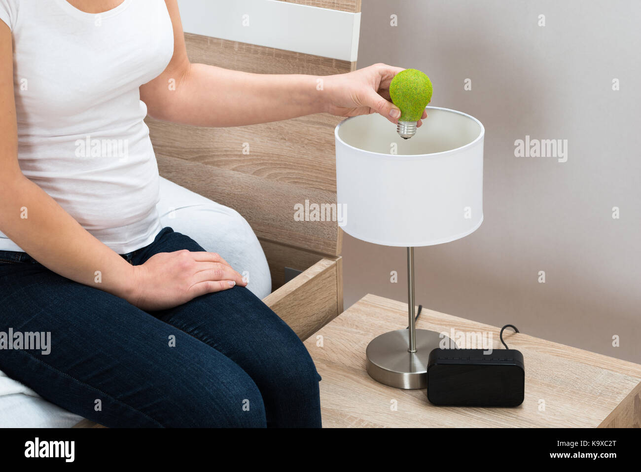 Close-up di persona il fissaggio a mano eco lampadina nella lampada da tavolo Foto Stock