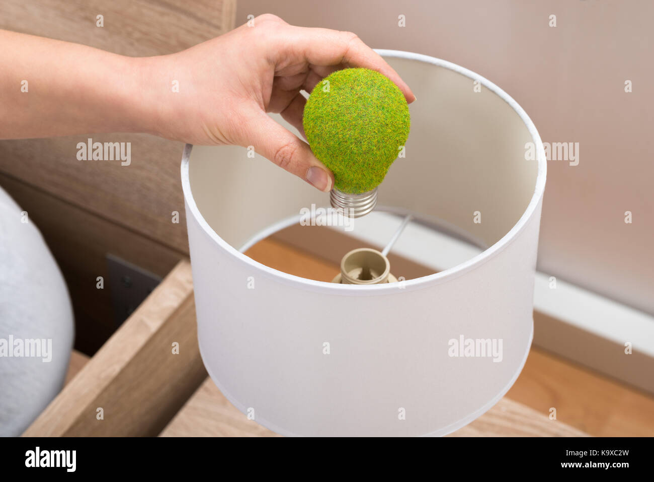Close-up di persona il fissaggio a mano eco lampadina nella lampada da tavolo Foto Stock