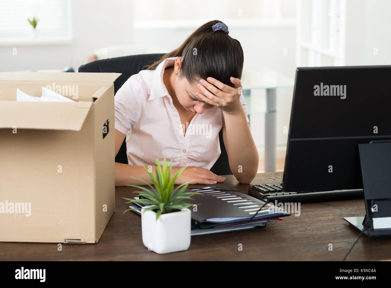 Giovane imprenditrice sconvolto seduto alla scrivania in ufficio Foto Stock