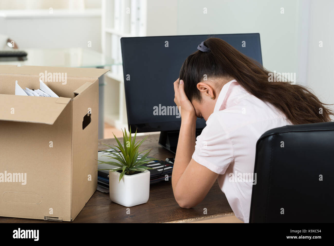 Chiudere giovane imprenditrice con averi seduto alla scrivania in ufficio Foto Stock