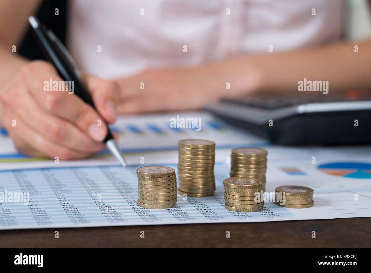 Close-up di commercianti con la pila di monete su grafico e relazione Foto Stock