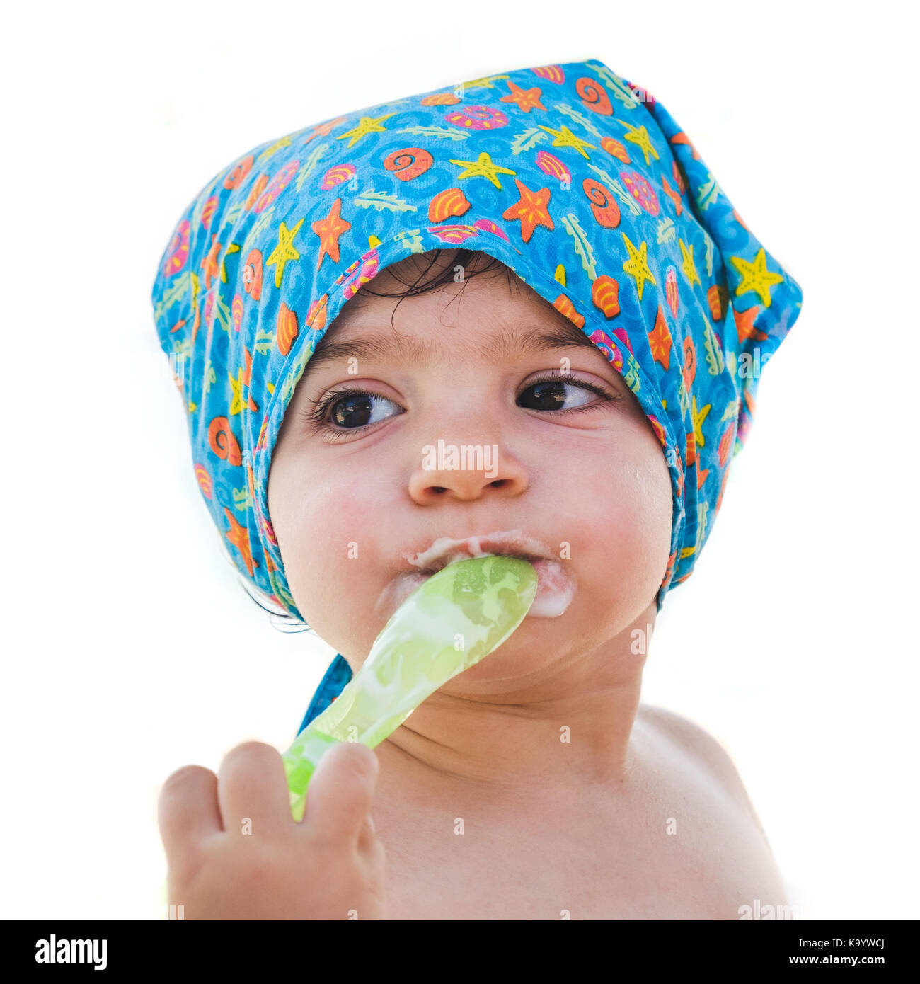 Cucchiaio per neonato mangiare stesso isolato bandana faccia bambino estate mare outfit Foto Stock