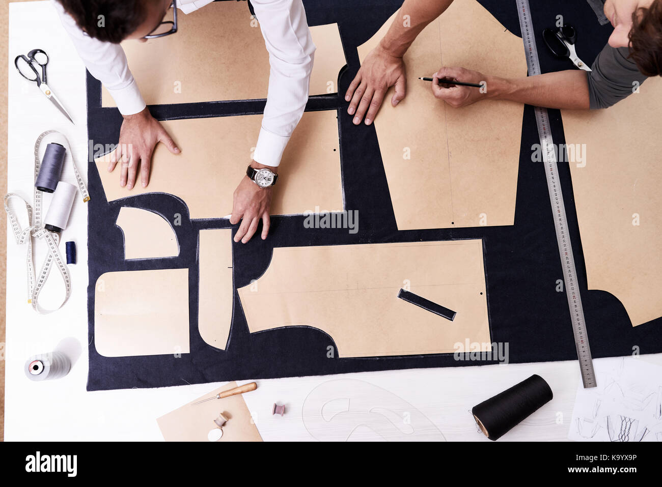 Alta Vista angolo di concentrato di giovani sarti utilizzando i modelli di cucitura mentre si lavora sulla creazione di custom-made camicia maschile Foto Stock