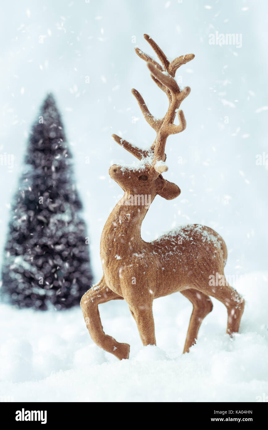 La renna animale la figura e l'albero di natale in scena di neve Foto Stock
