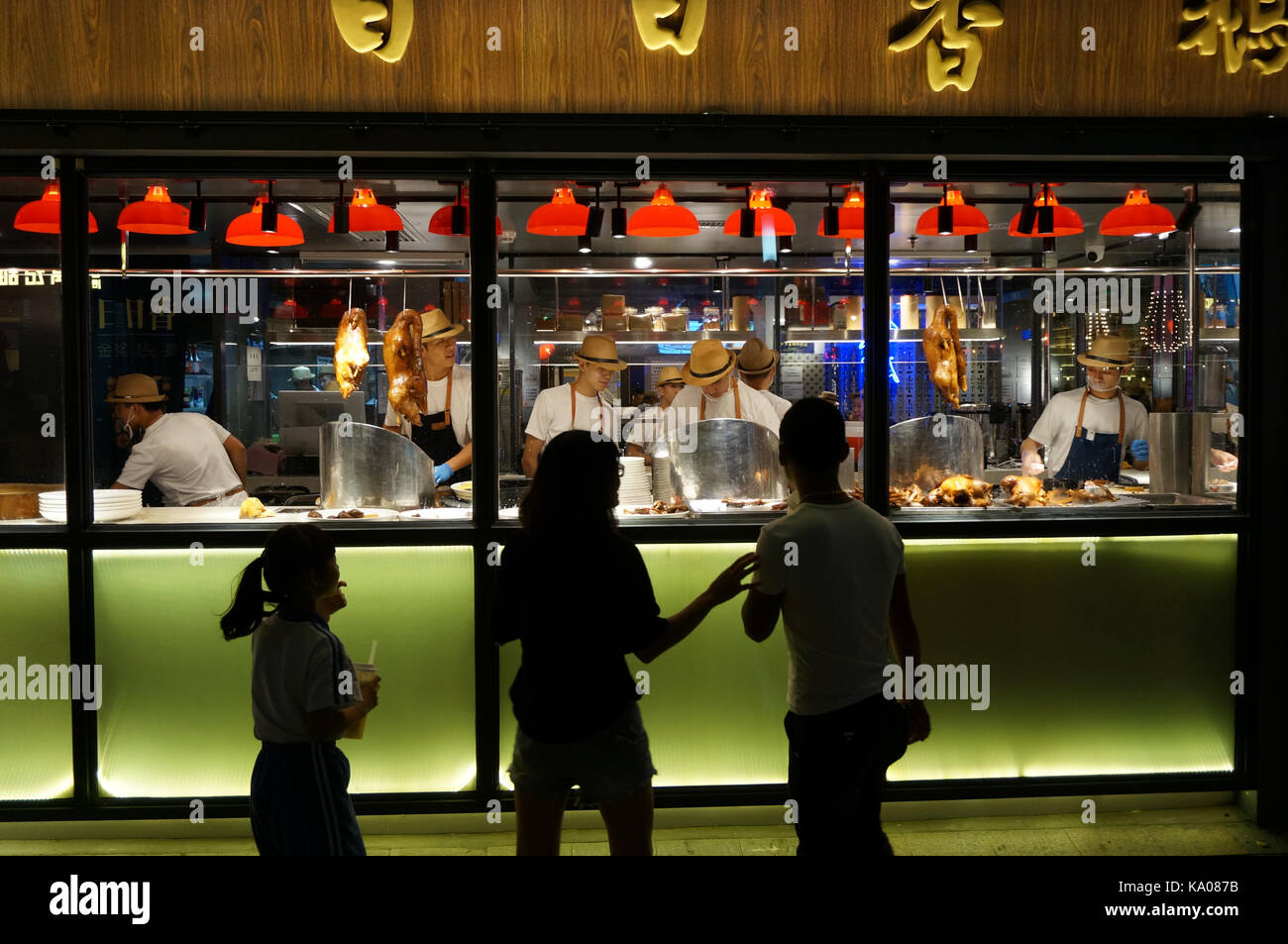 Il ristorante cinese lavoratori visto dietro una finestra di trinciatura anatre arrosto come guardare le persone lavorano in shenzhen, Cina Foto Stock