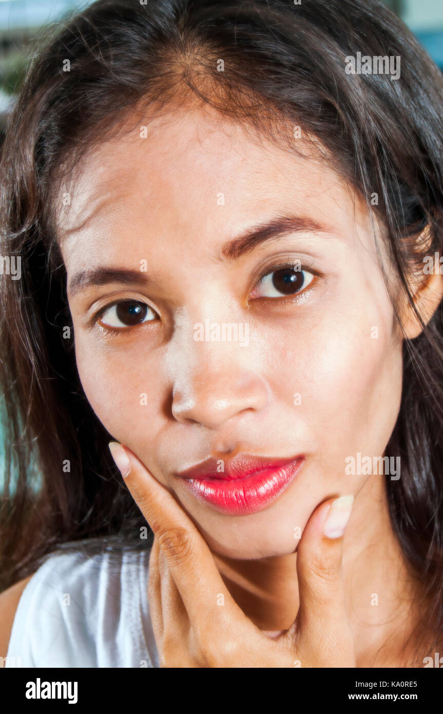 Tiro al coperto all'aperto con sfondo di una giovane donna asiatica facendo un gesto con la mano sul suo viso Foto Stock
