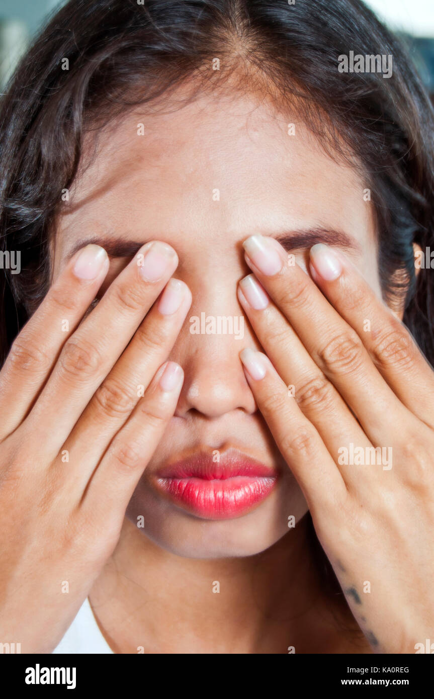 Tiro al coperto all'aperto con sfondo di una giovane donna asiatica facendo un gesto con la mano sul suo viso Foto Stock