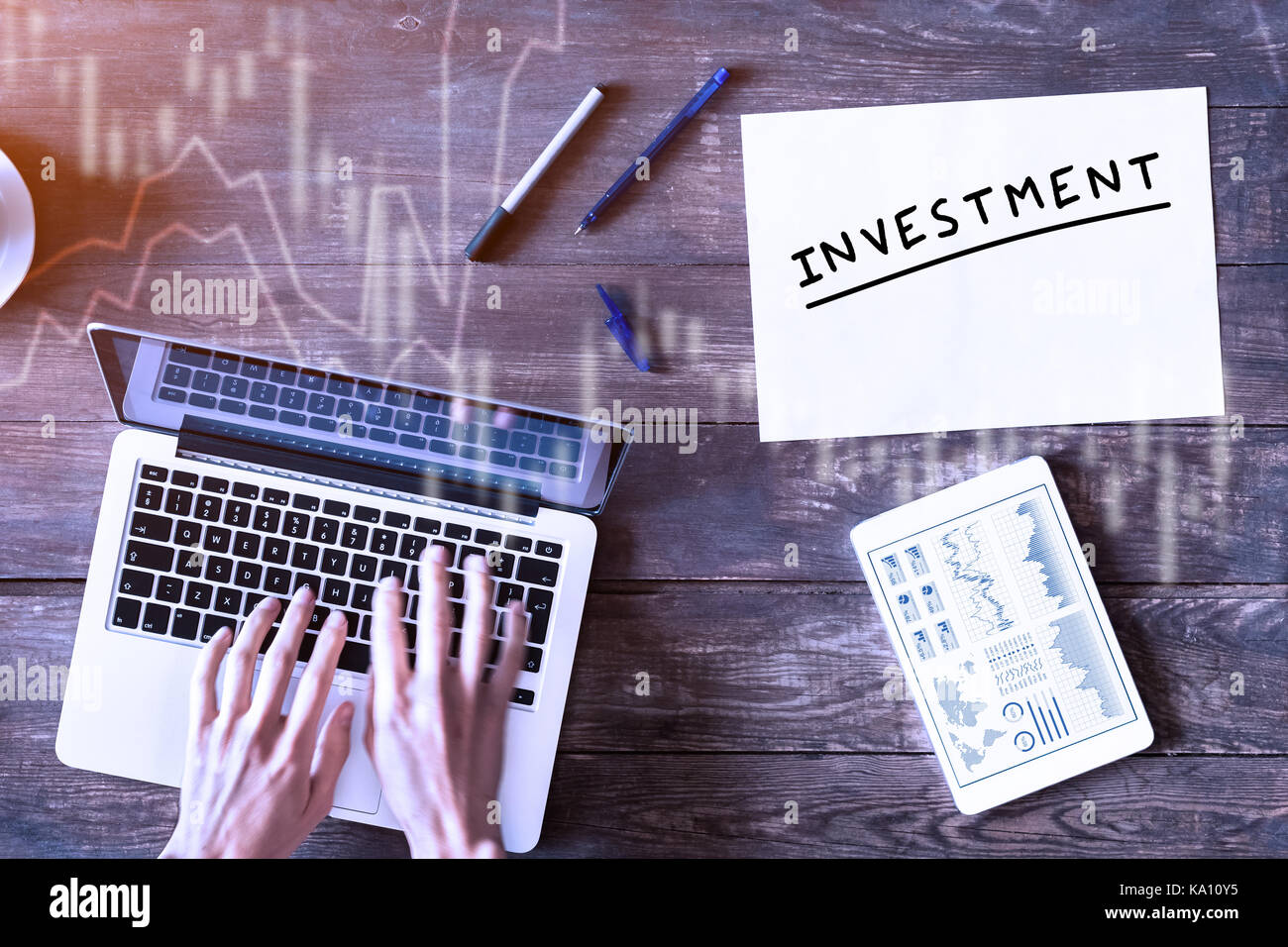 Concetto di investimento con il business persona digitando su computer e finanziario sul cruscotto digitale compressa, vista da sopra un tavolo di legno Foto Stock