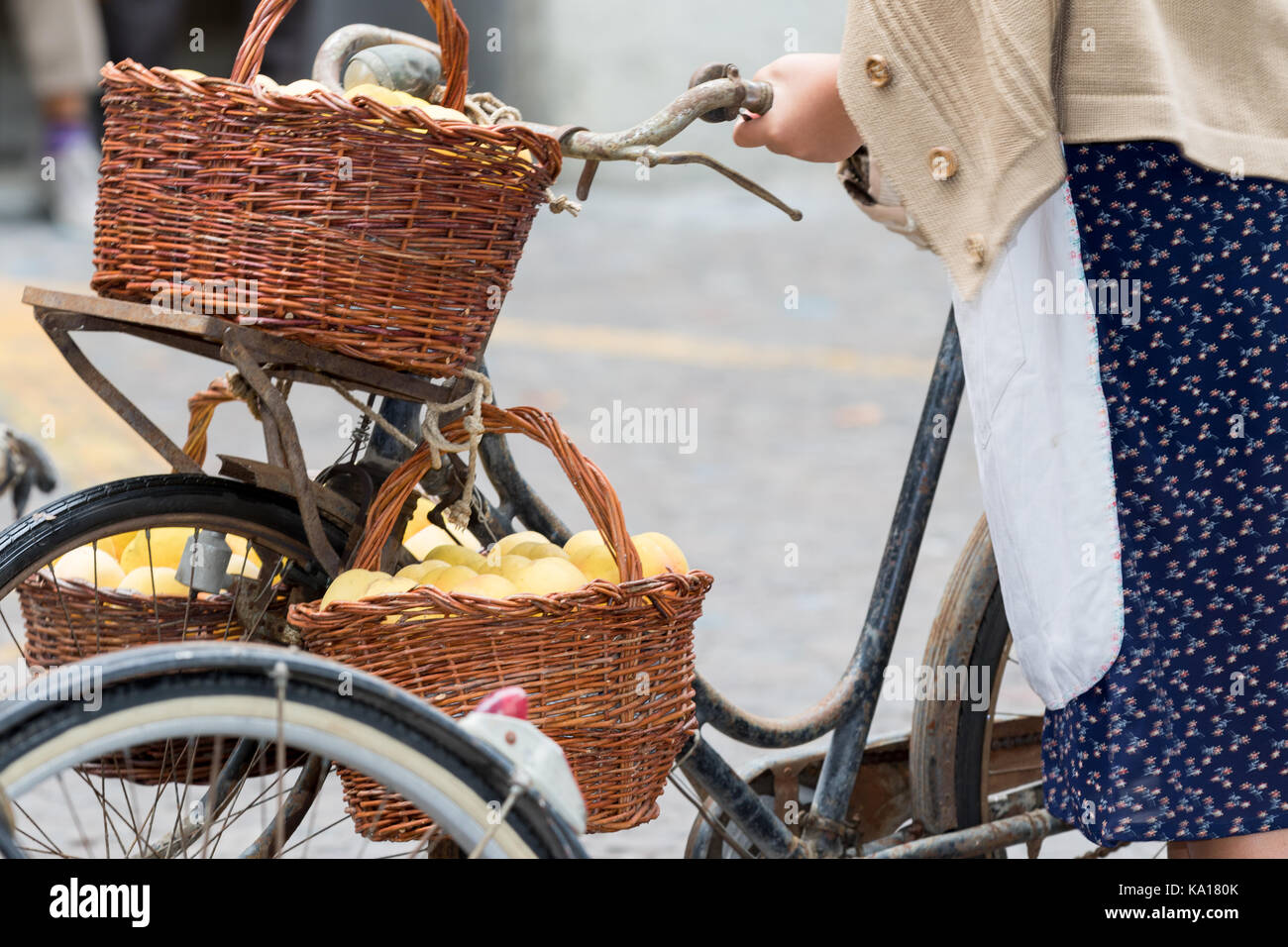 Asti, Italia - 10 settembre 2017: donna vestito in abiti antichi porta pesca gialla cesti su una vecchia bicicletta Foto Stock
