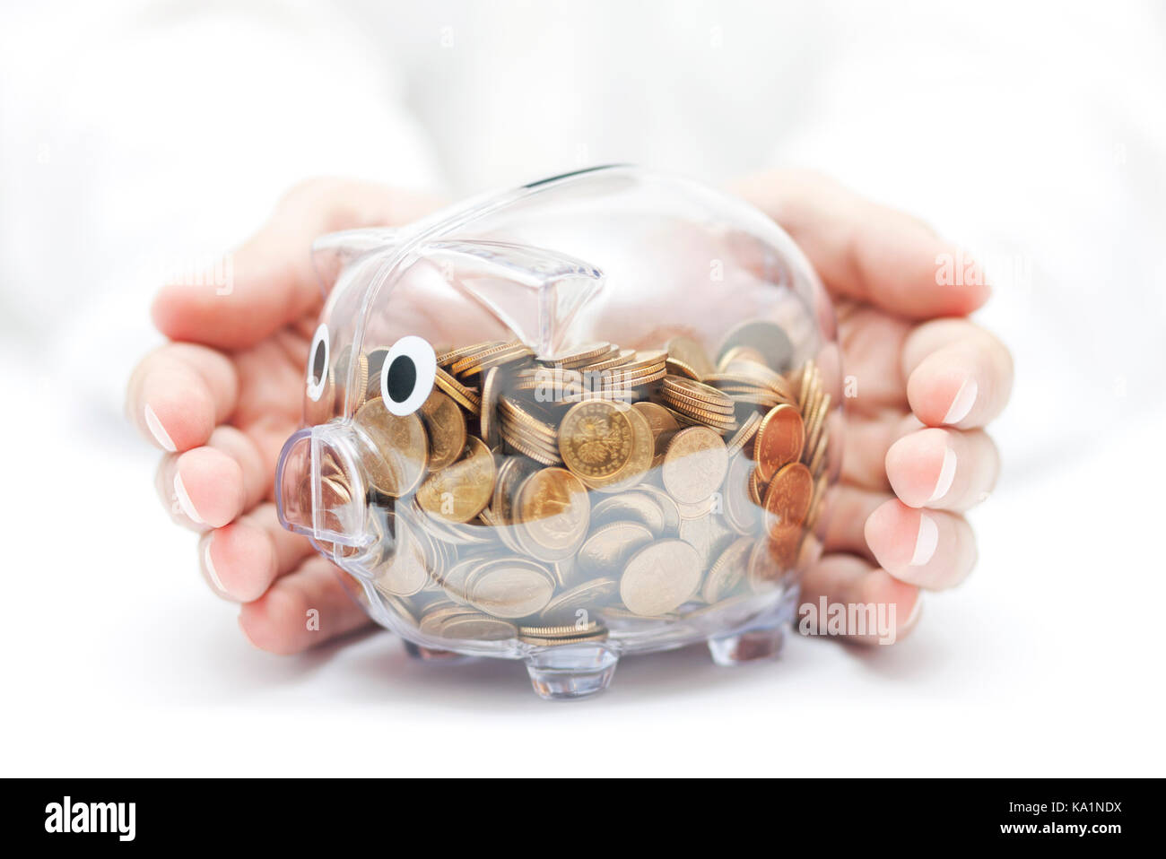 Proteggere il tuo denaro trasparente salvadanaio con monete coperti da mani. Foto Stock