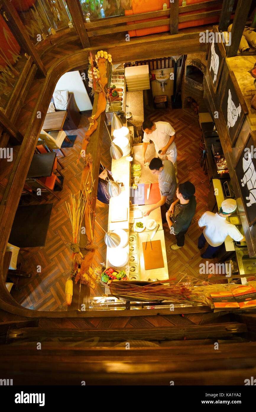 La vista al di sopra del barman in piedi dietro il bancone bar e di servire il cunstomer nella caffetteria decorata in stile in legno. Foto Stock