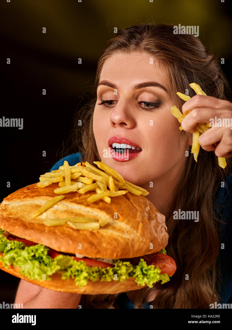 Donna di mangiare patatine e hamburger. Foto Stock