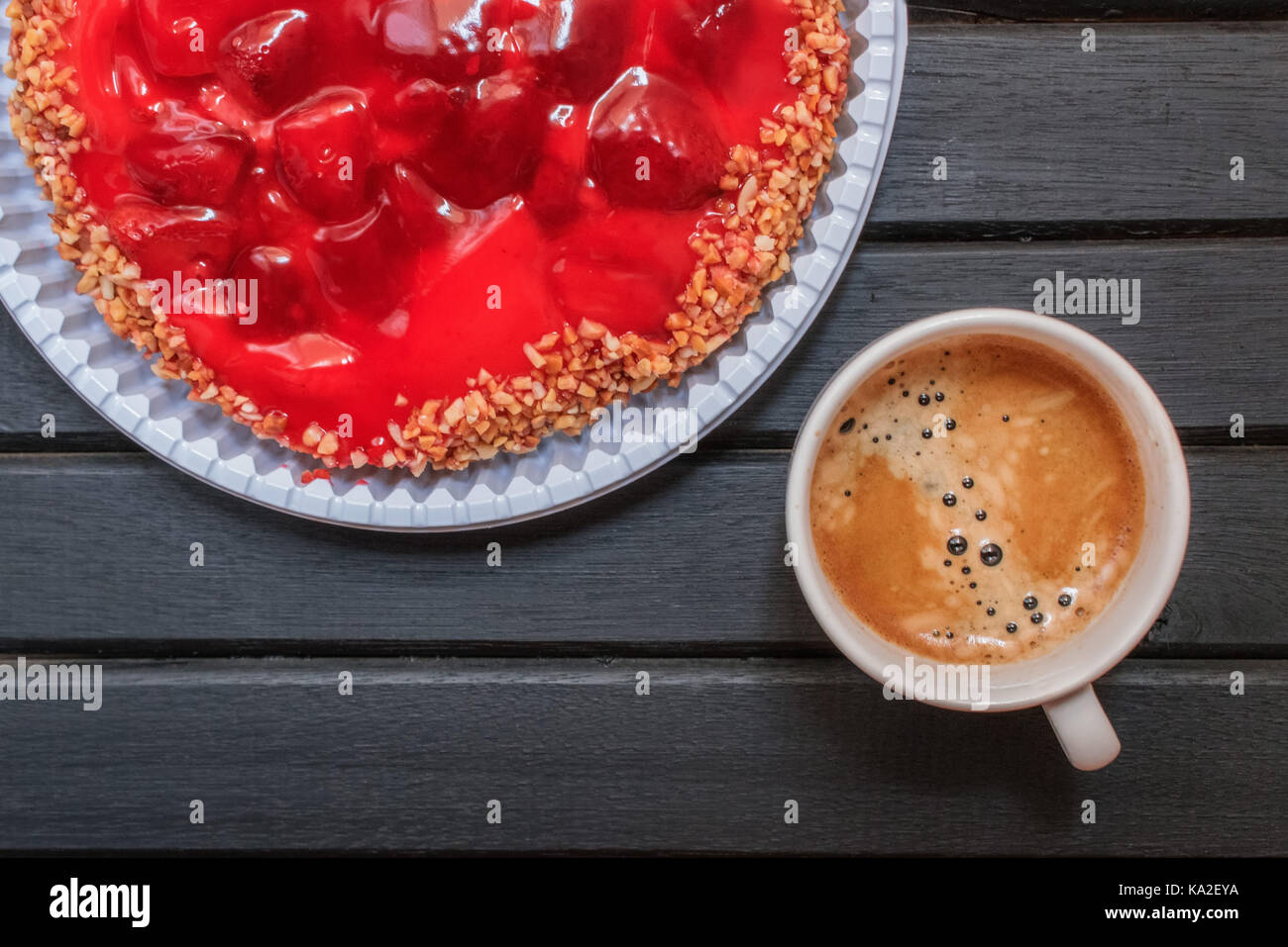 Fragola rossa torta dolce su un di legno nero e sfondo freschi di infuso di caffè espresso su una tazza bianca Foto Stock