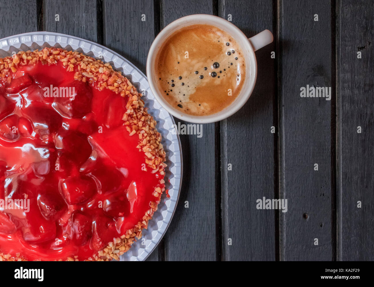 Fragola rossa torta dolce su un di legno nero e sfondo freschi di infuso di caffè espresso su una tazza bianca Foto Stock