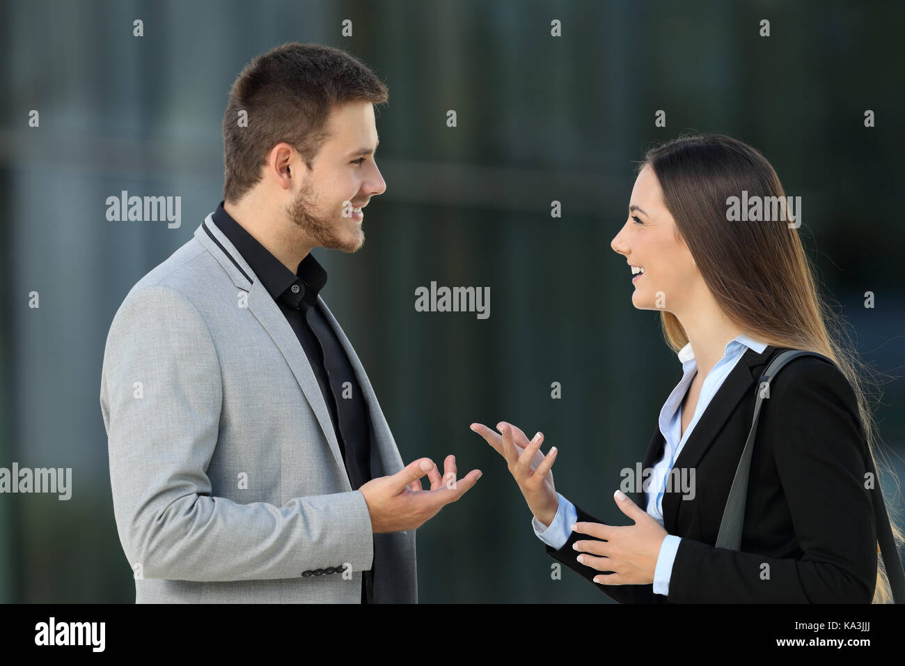 Vista laterale verticale di una coppia felice dei dirigenti a parlare su strada Foto Stock
