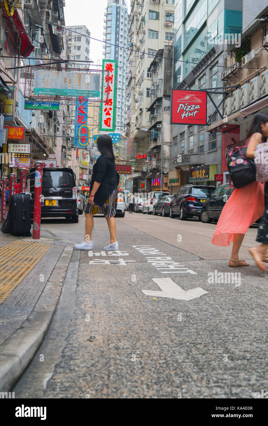 Hong kong, asia - agosto 2, 2017; persone cross street in scena tipicamente asiatico con pletora insegne al neon di hong kong Foto Stock