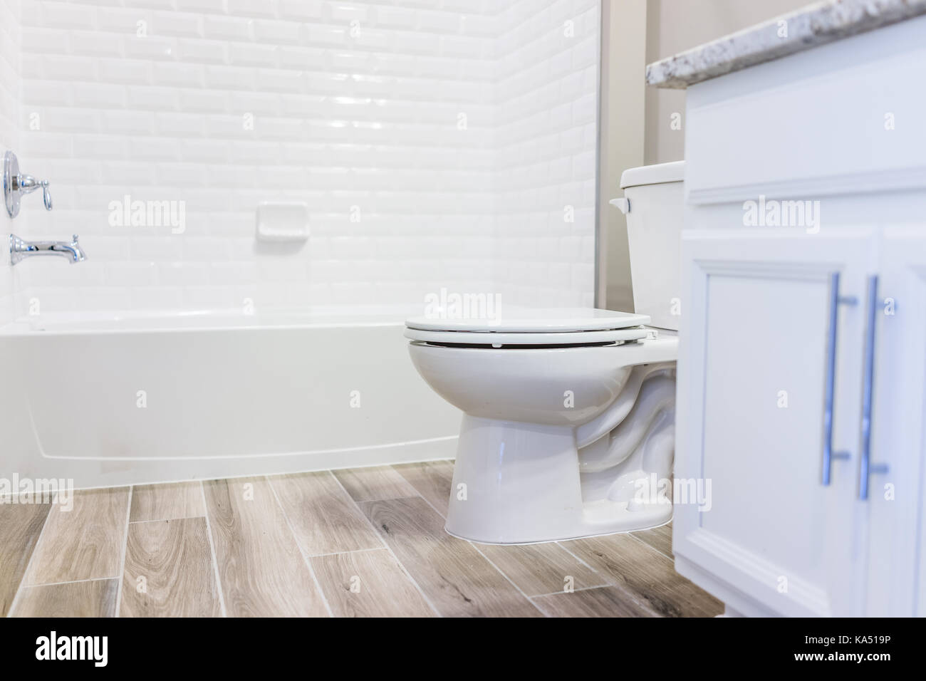 Bianca e moderna pianura pulire wc bagno vasca con doccia piastrelle e pavimenti in legno duro con staging in modello di casa di staging, casa o appartamento Foto Stock